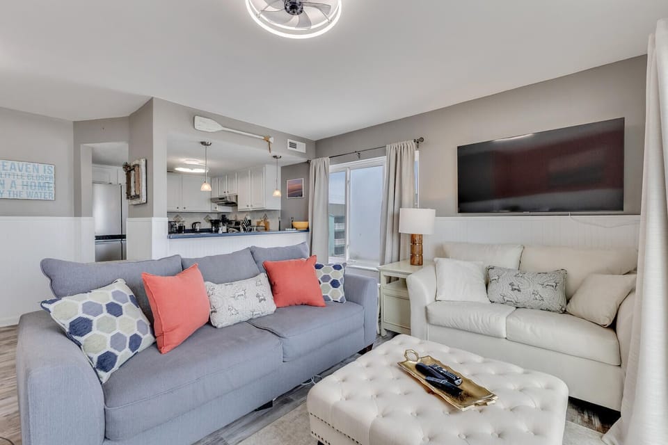 Settle into your stylish living space where soft blues and warm coral pillows invite relaxation on plush seating.