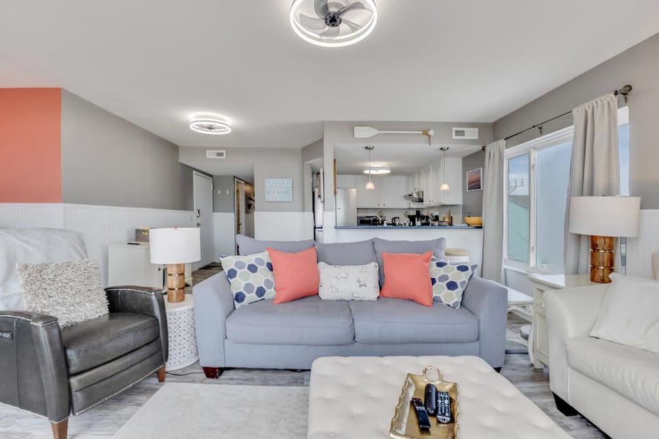 Relax in your stylish living room with plush seating and coral accents. The open-plan design connects seamlessly to your fully-equipped kitchen.