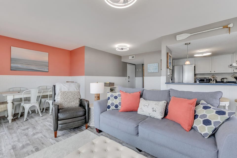 Relax in your bright, coastal-themed living space with plush seating and vibrant coral accents that create the perfect beach getaway atmosphere.