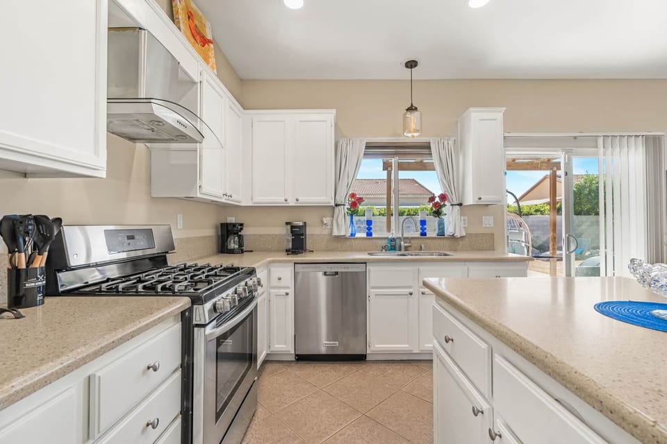 Modern kitchen with white cabinets, neutral counters, stainless appliances, and a spacious island.