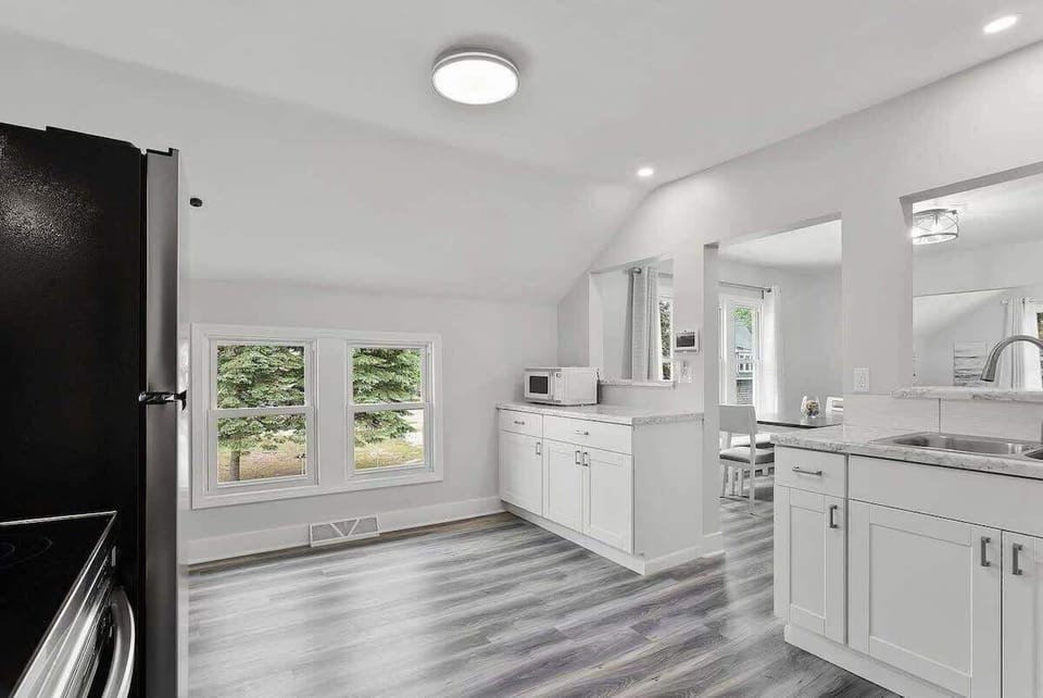 Open kitchen layout with the bathroom and dining room off the kitchen. Kitchen sink overlooks the dining room and living room. Kitchen features granite countertops and a microwave. 
