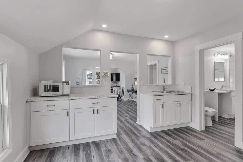 Open kitchen layout with the bathroom and dining room off the kitchen. Kitchen sink overlooks the dining room and living room. Kitchen features granite countertops and a microwave. 