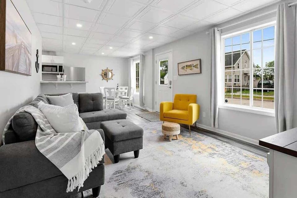 Comfortable living room with couch and chair that is open to the kitchen and dining area. Features a smart tv. 