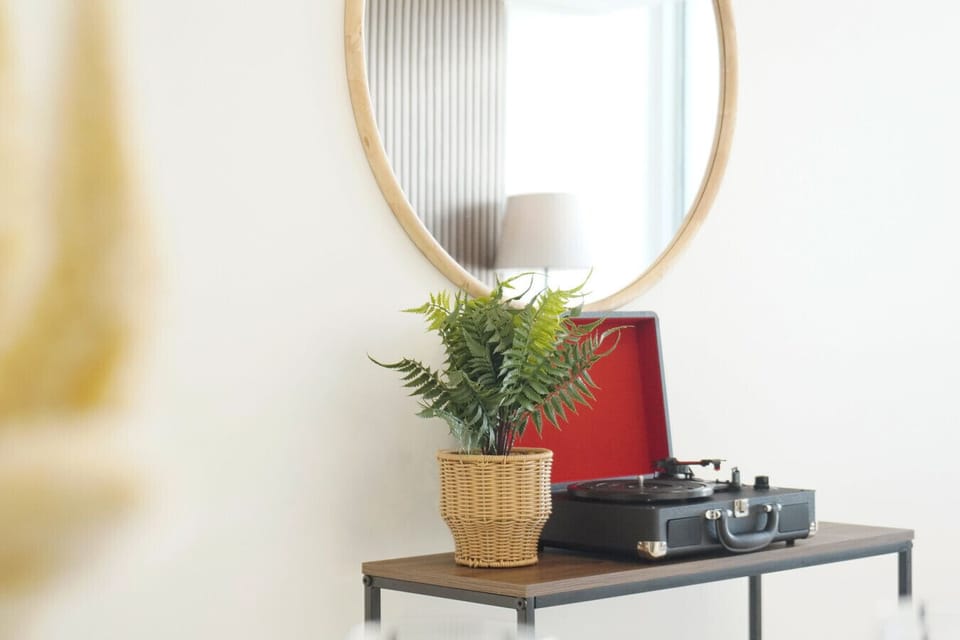 A stylish vignette featuring a round statement mirror, woven greenery, and a vintage-inspired record player — the perfect blend of comfort and character.