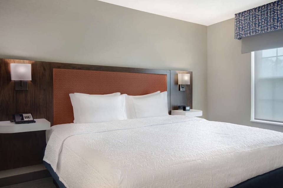 King bed with soft white sheets and wall lights on both sides