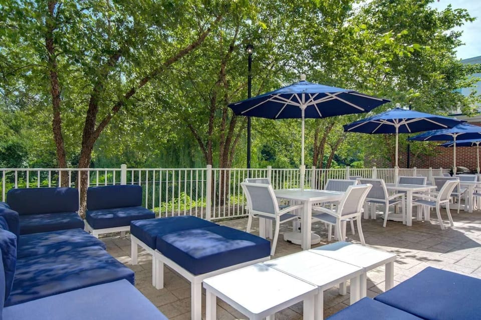 Sunny outdoor area with blue umbrellas and white patio furniture