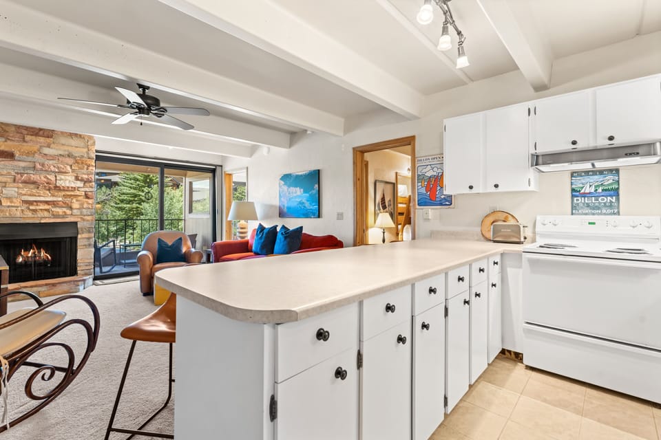 Gather in your bright, open living space with cozy fireplace warmth, a fully equipped kitchen for home-cooked meals, and a private balcony framing the surrounding greenery.