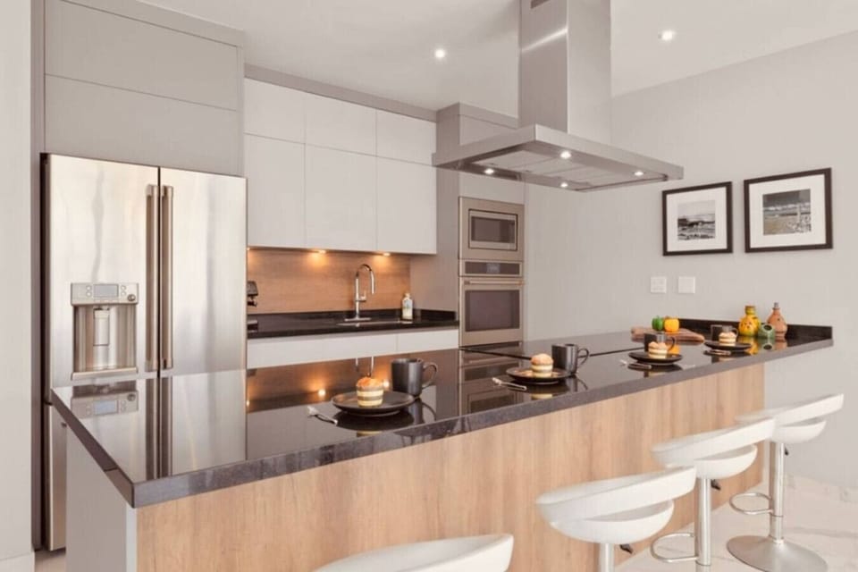 Fully equipped contemporary kitchen featuring a large breakfast bar and sleek stainless steel appliances.