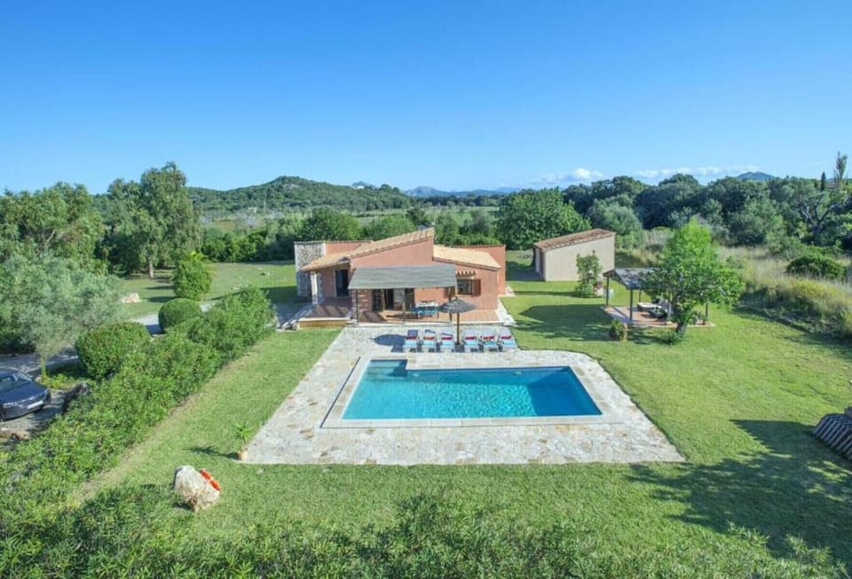 Vista aérea de villa vacacional en Pollensa con piscina privada y amplios jardines.