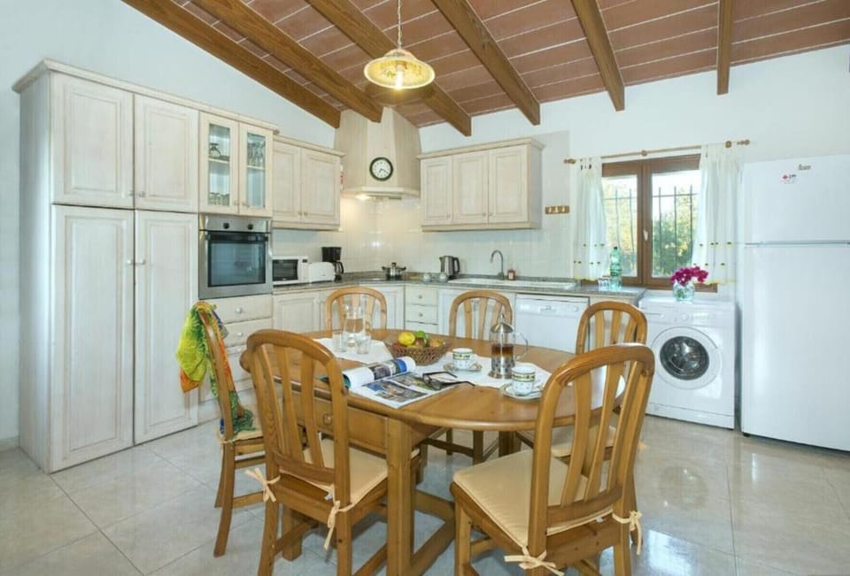Bright spacious kitchen with dining table, full appliances and wooden ceiling in a Pollensa holiday villa.