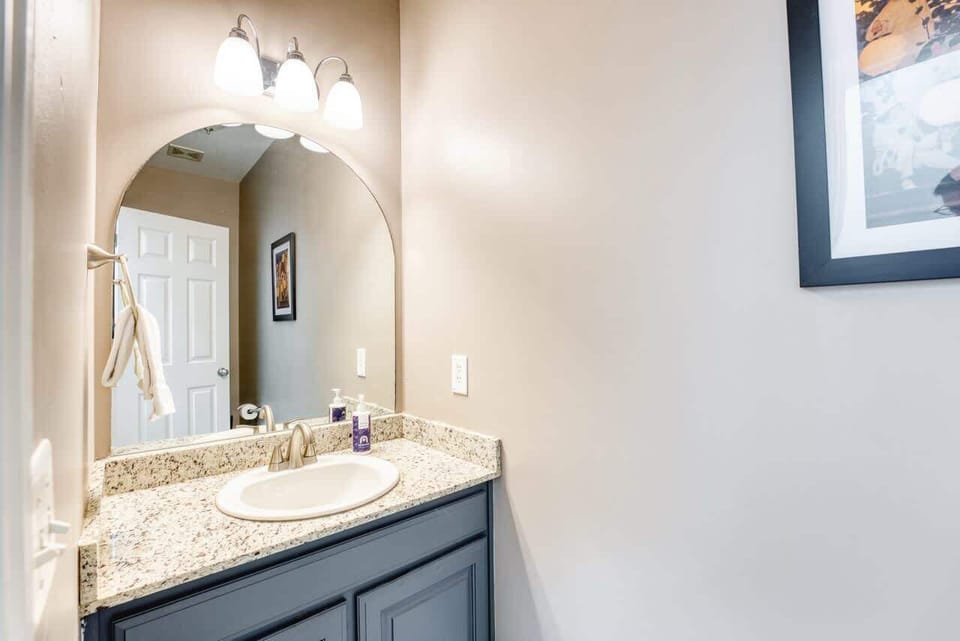 Elegant vanity with granite counter, arched mirror, and modern fixtures—stocked with hand soap and essentials for your stay.