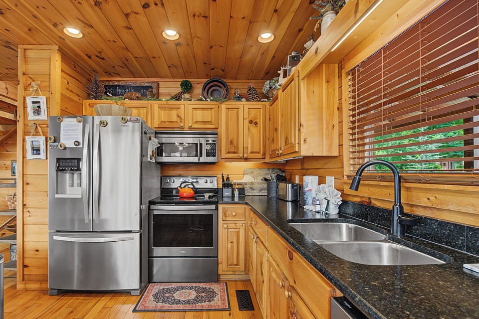 Your fully-equipped kitchen features warm wood cabinetry, stainless steel appliances, and granite countertops—perfect for preparing meals together during your mountain getaway.