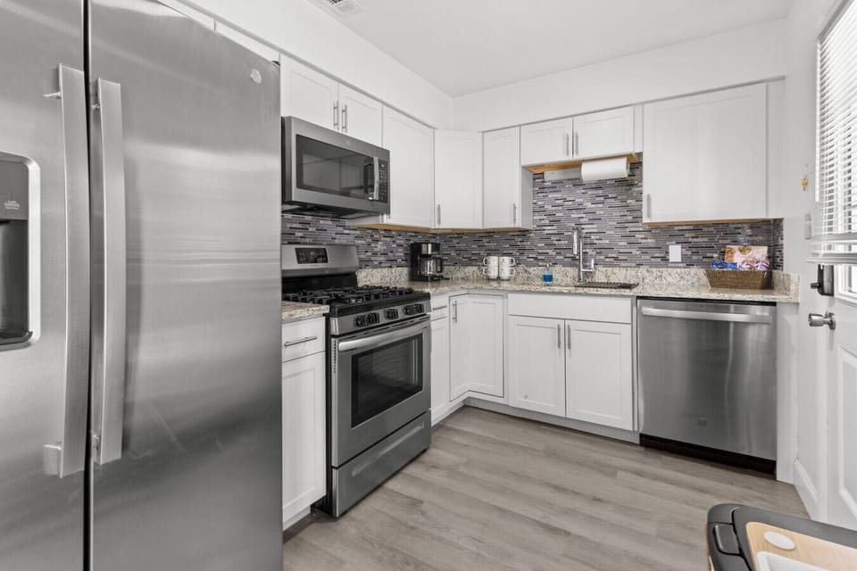 Modern kitchen with stainless steel appliances and full cookware.
