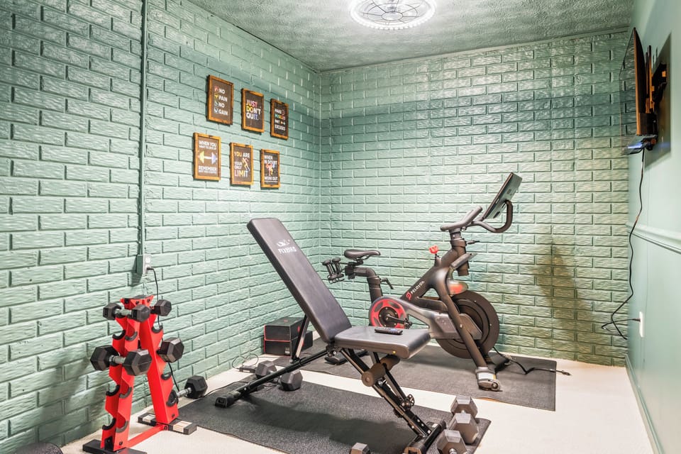 Private fitness room featuring a Peloton bike, free weights, and adjustable bench.