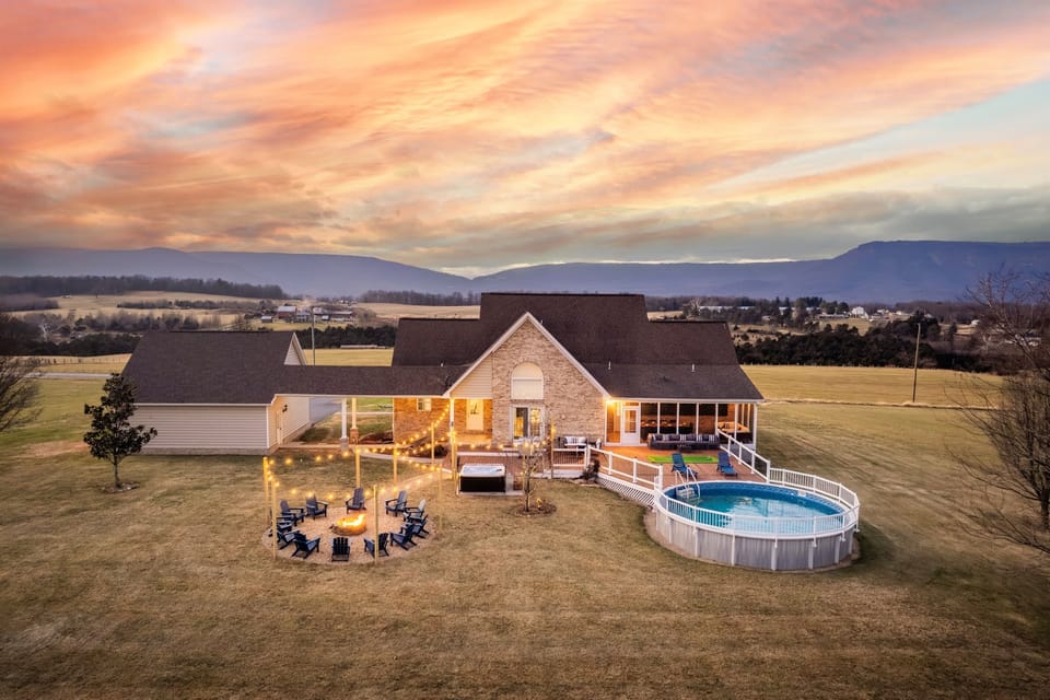Sunset-view home with glowing string-lit firepit, private pool, hot tub, and wide open mountain panoramas—perfect for unforgettable gatherings under the sky at Luray Vista.