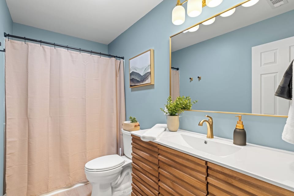 Bedroom 3 ensuite with wood vanity, gold fixtures, and mountain art. Stylish and spa-inspired.