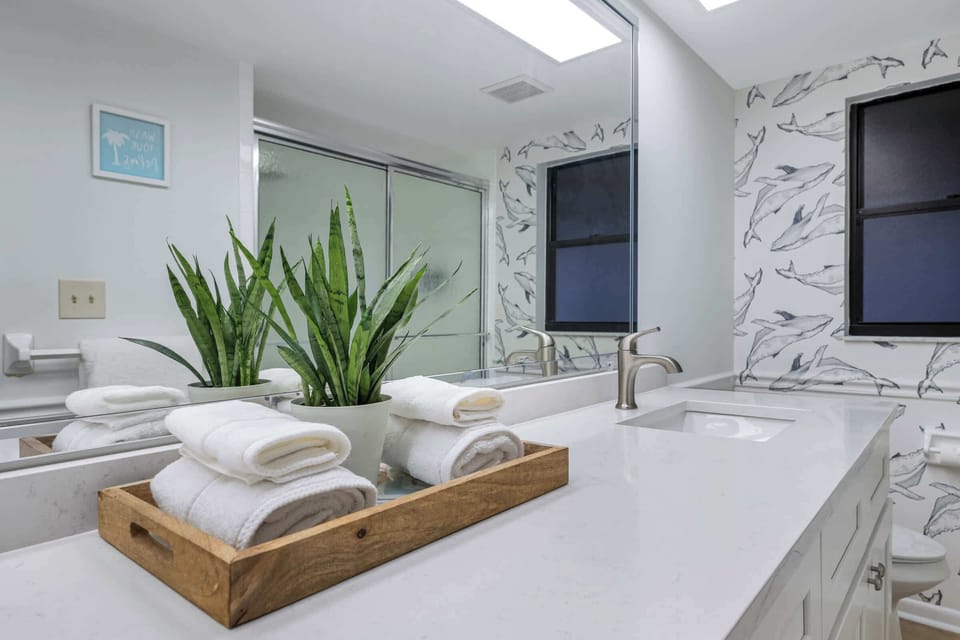Playful whale wallpaper and a quartz-topped vanity brighten this full bath. - Whale Wallpaper Bath - The Hammock - Largo, FL