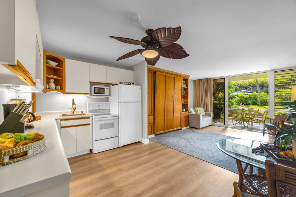 Savor the convenience of an open-plan design with a modern kitchen, ceiling fan, and sliding glass doors leading to a private lanai.