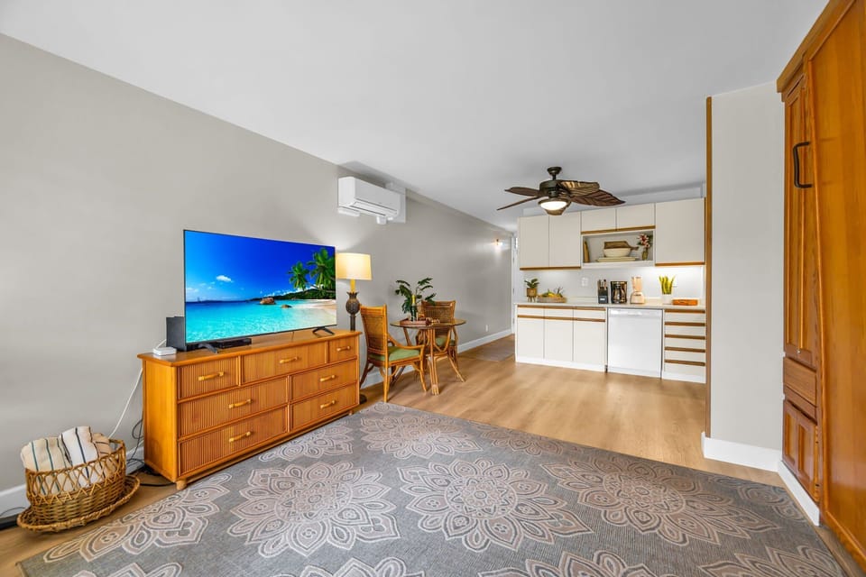 Enjoy a spacious interior with a flat-screen TV, warm wood furnishings, and an open layout that flows seamlessly toward the kitchen.