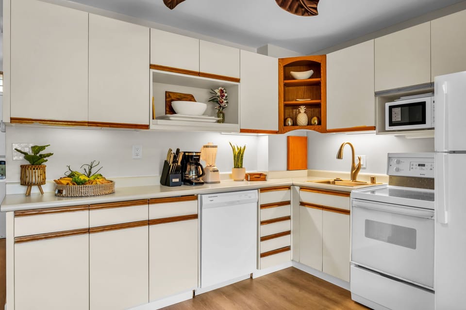 Cook with ease in a well-equipped kitchen showcasing white cabinetry with natural wood trim, modern appliances, and thoughtful touches of greenery.