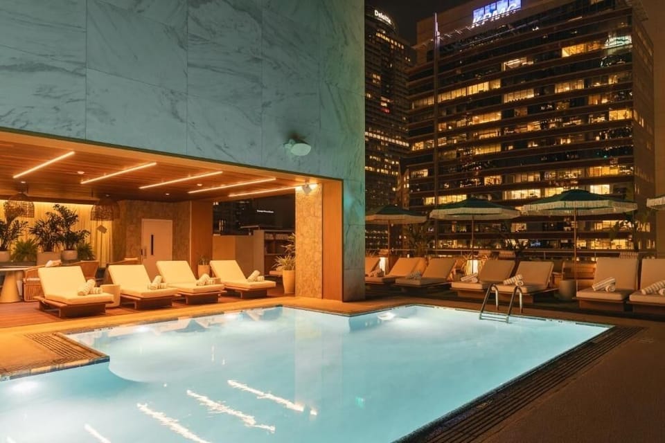 Unwind poolside under city lights with plush loungers.