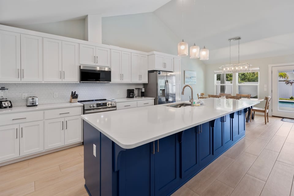 Your gourmet kitchen features a stunning blue island, gleaming countertops, and top-tier appliances—perfect for creating memorable meals together.