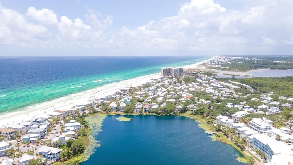 Stunning aerial view showcasing pristine white sand beaches, turquoise Gulf waters, and coastal lake community.