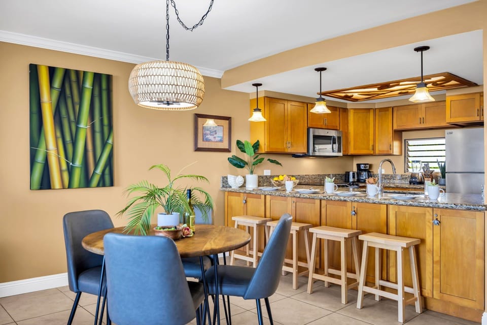 Dining area with round table, blue chairs, and modern kitchen.