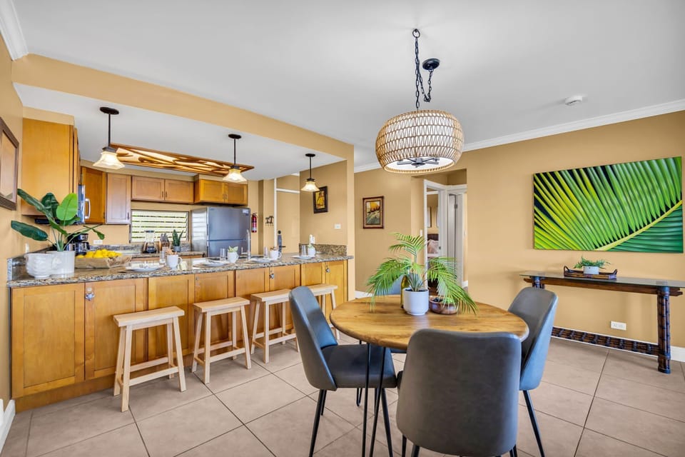 Dining area with wooden table, bar stools, and stainless kitchen appliances.