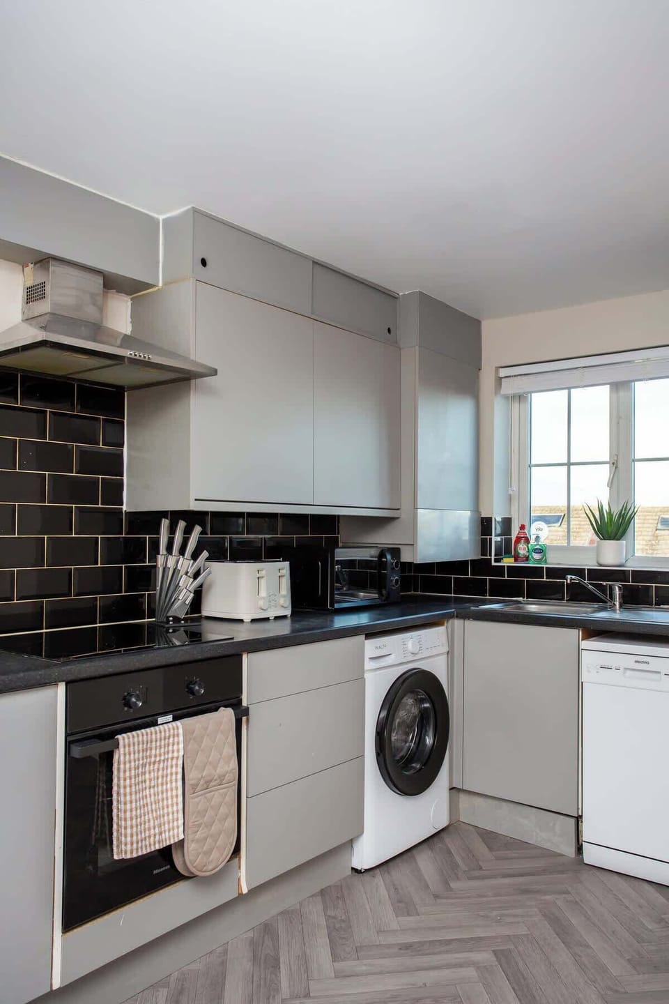 Fully equipped kitchen featuring oven, hob, microwave, and washing machine.