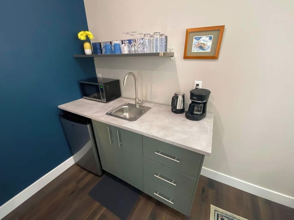 Kitchenette includes mini fridge, microwave, sink, coffee maker, and kettle. Appointed with dishes, glassware, coffee & tea.