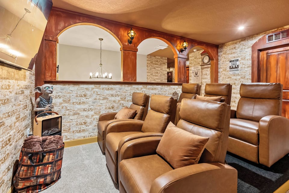 Enjoy a cozy movie night in this inviting home theater, complete with plush leather recliners that invite you to relax. Warm lighting and charming stone walls create the perfect atmosphere for unforgettable entertainment.