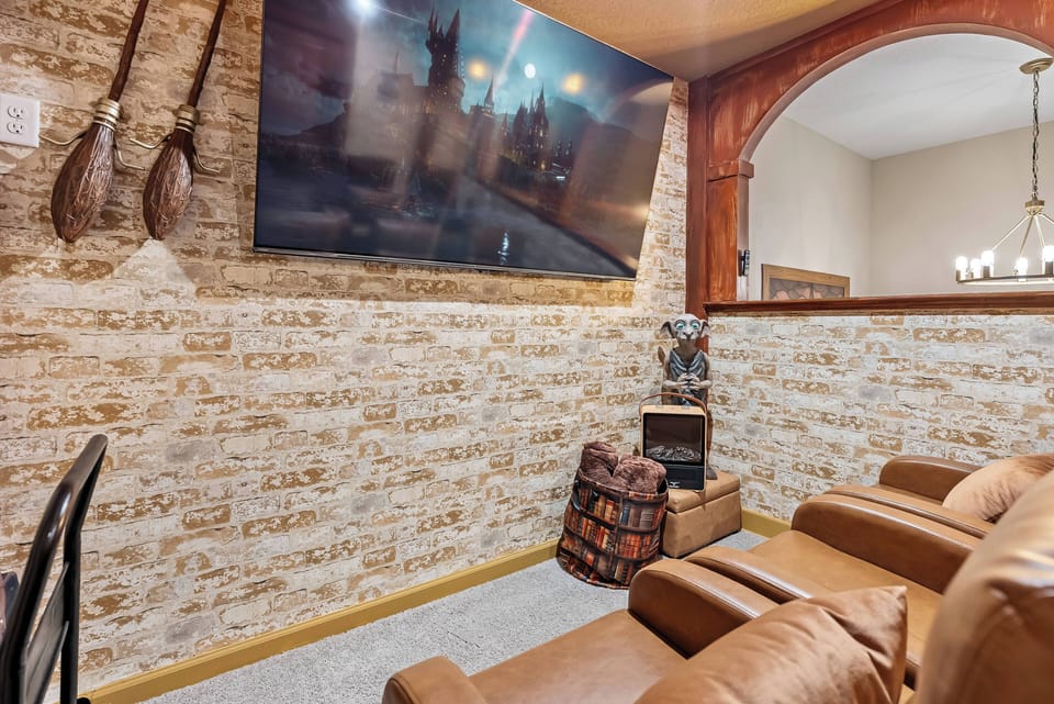 Unwind in this cozy living area with a beautiful stone accent wall, comfortable leather seating, and a large flat-screen TV for entertainment, all creating an inviting atmosphere perfect for relaxation.