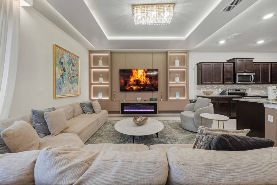 Experience a stylish living area with plush sofas inviting you to relax under warm lighting. The chic decor, featuring a modern fireplace and striking artwork, perfectly blends comfort and sophistication for your enjoyment.