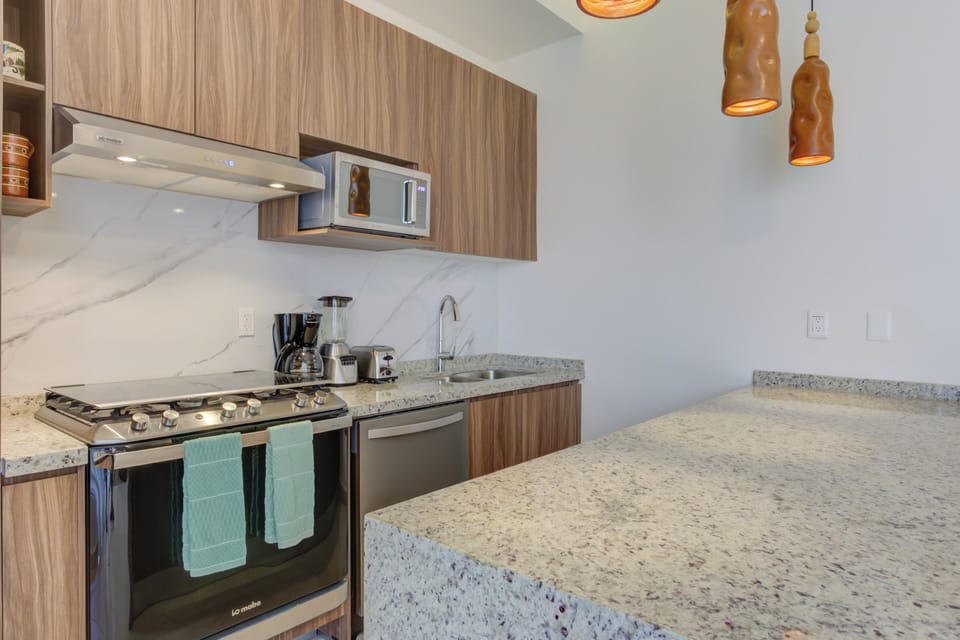 Cook in style inside a modern chef's kitchen, boasting premium wood cabinetry, high-end stainless-steel appliances, and a polished granite prep island.