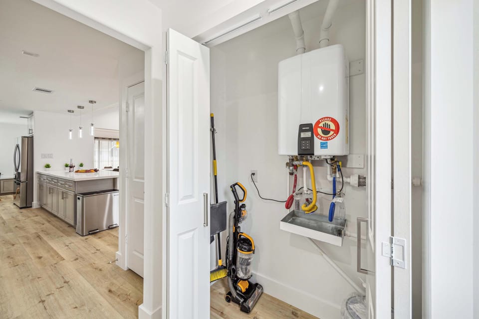 A Neat Utility Closet With A Tankless Water Heater And Cleaning Supplies, Adjacent To The Modern Kitchen