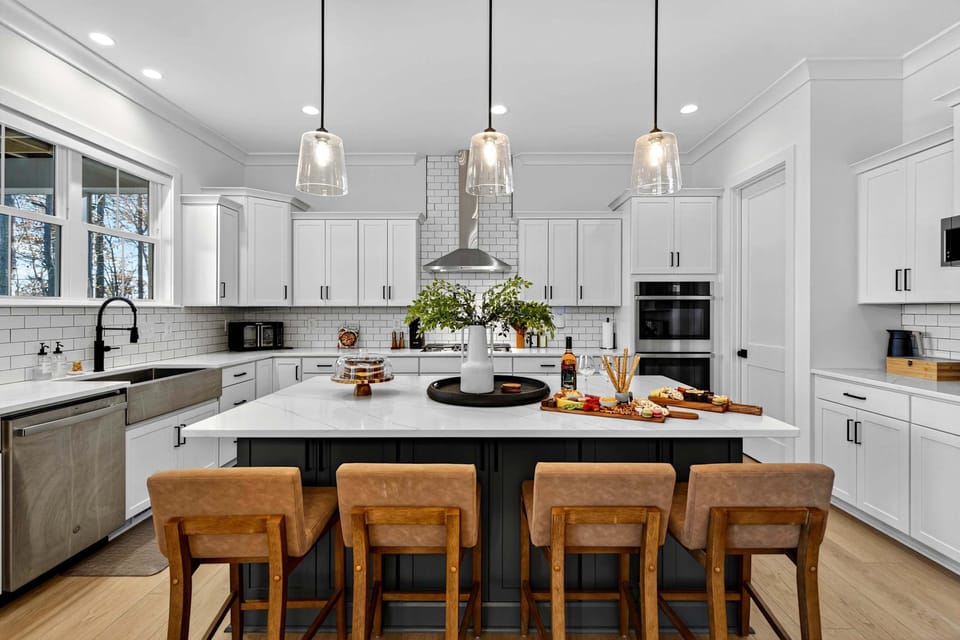 Gourmet Kitchen - A massive quartz island with seating for four, pendant lighting, subway tile backsplash, and stainless steel appliances.