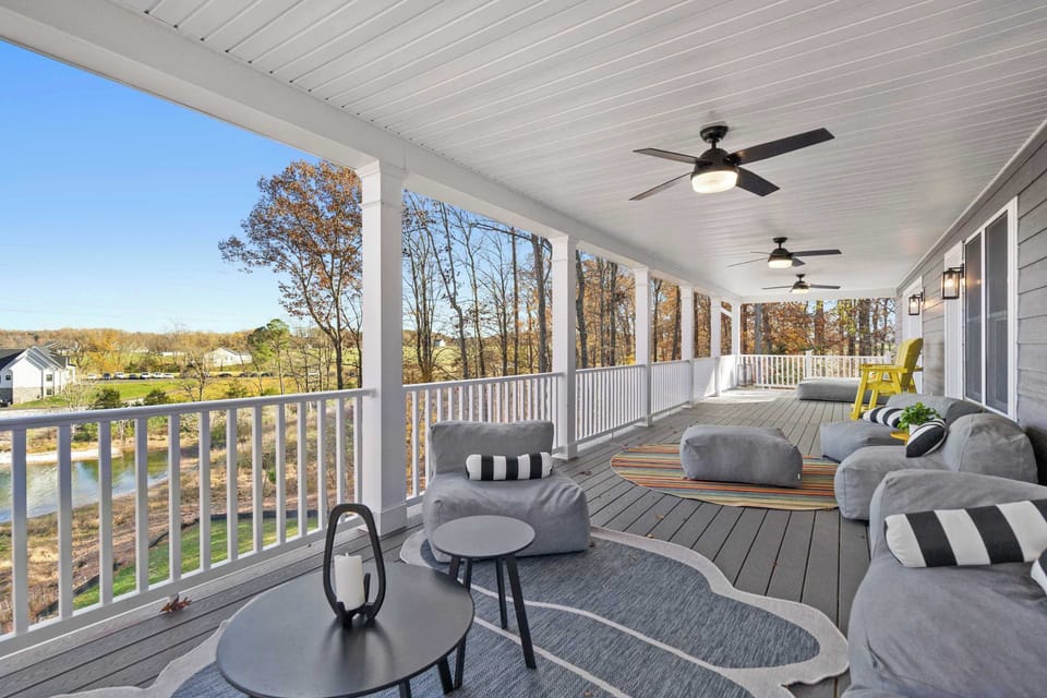 Wraparound Porch - Multiple seating areas stretch across the covered deck, with lake views peeking through the trees.