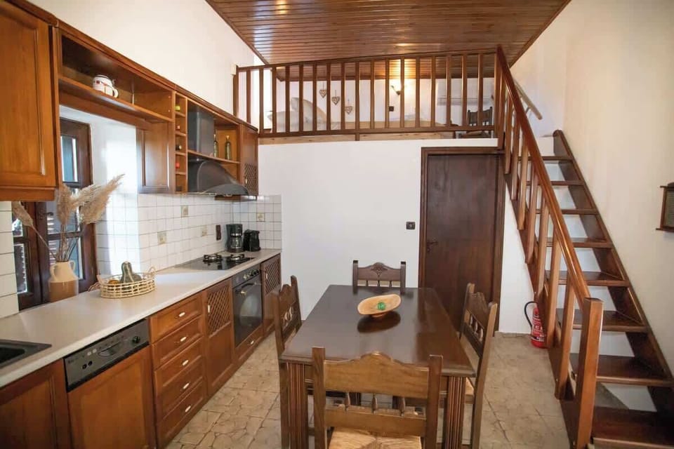 Functional kitchen area with wooden elements and an interior staircase leading to the loft, enhancing the home’s unique traditional structure