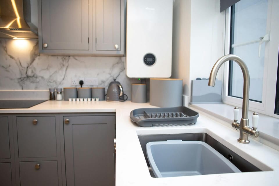 Kitchen with washing up sink, window, hob and cooker hood