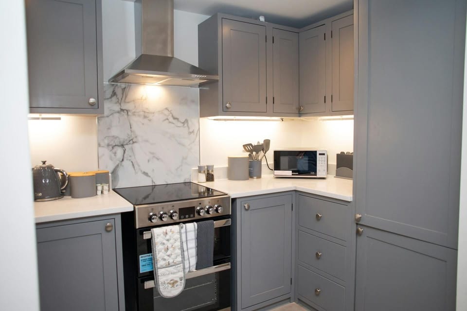 Kitchen with fitted cupboards, oven, hob, extractor hood, kettle and toaster