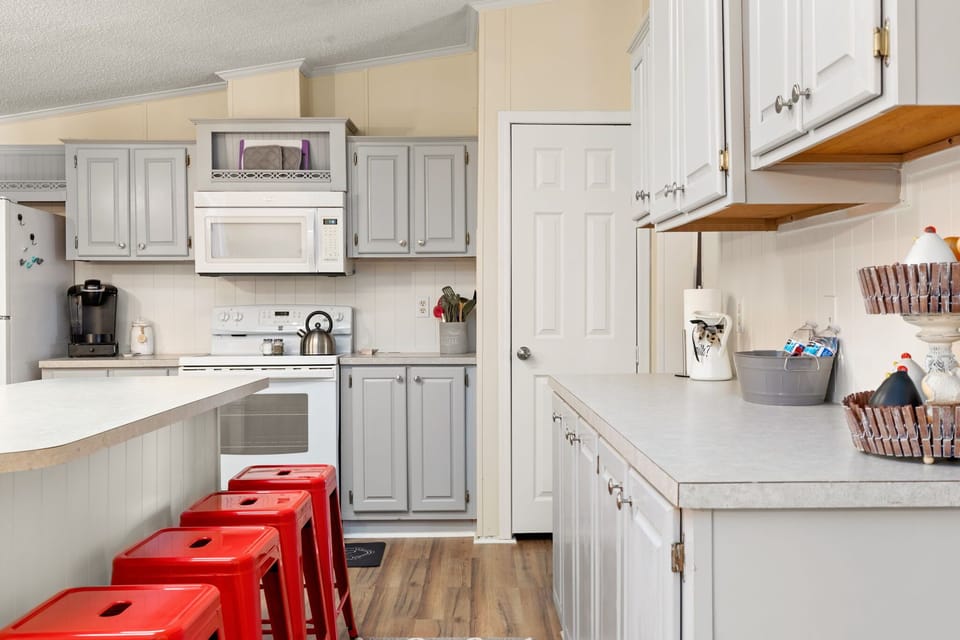 A fully equipped kitchen with a large island and bright red stools. Perfect for meal prep, casual dining, and morning coffee before a busy day.