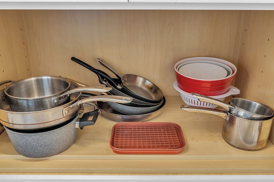 Stainless pots, non-stick pans, bowls & drying rack ready for your cooking.