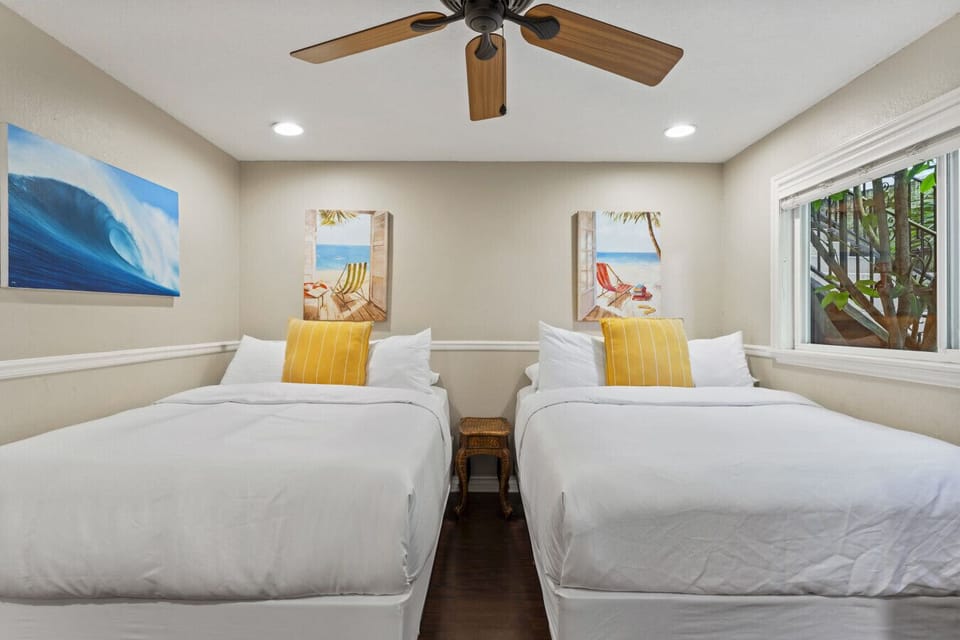 Comfortable bedroom w/ two beds, soft linens & natural light from nearby window