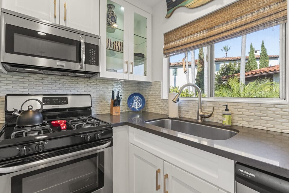 Sleek kitchen setup w/ modern appliances & window views at the sink