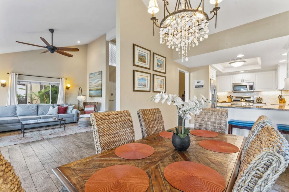 Open living & dining space w/ woven chairs, chandelier & seamless flow to the kitchen