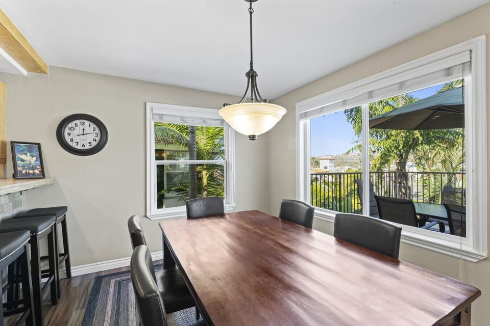 Dining area w/ wood table, chandelier lighting & windows bringing in natural light