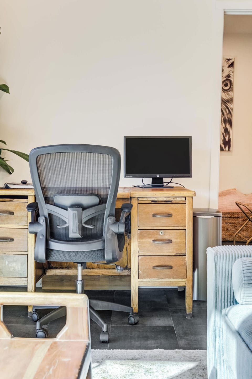 A dedicated workstation with a solid wood desk, ergonomic chair, and monitor creates a comfortable spot for remote work within the main living area.