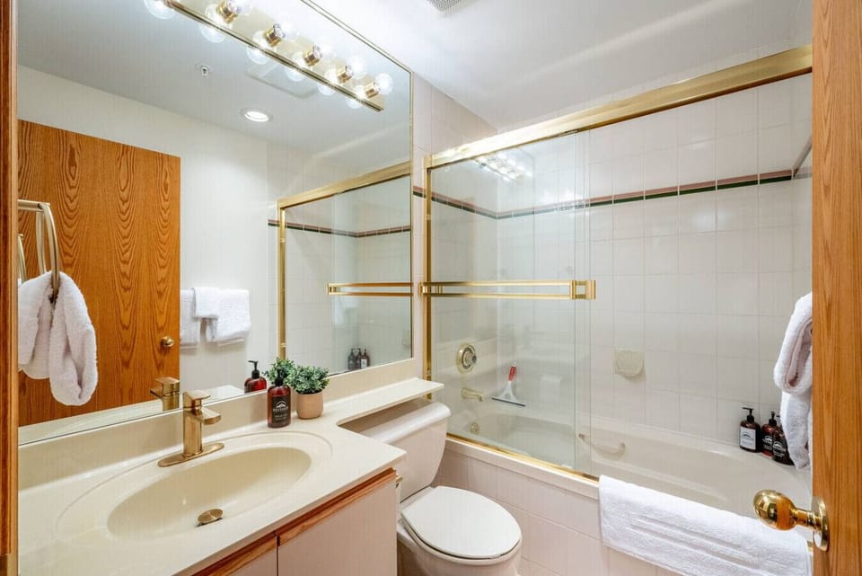 Clean and comfortable bathroom featuring a full bathtub, glass shower doors, and fresh towels for your stay. Bathroom amenities provided: Soap, shampoo and conditioner.