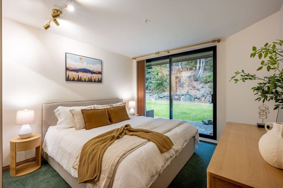 Bright king sized bed with direct patio access and peaceful forest views—perfect for a relaxing retreat.